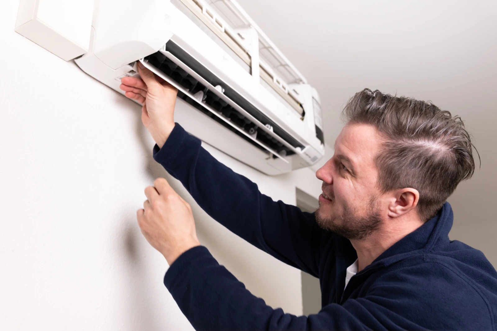 Techniker öffnet Klappe einer Klimaanlage zur Wartung